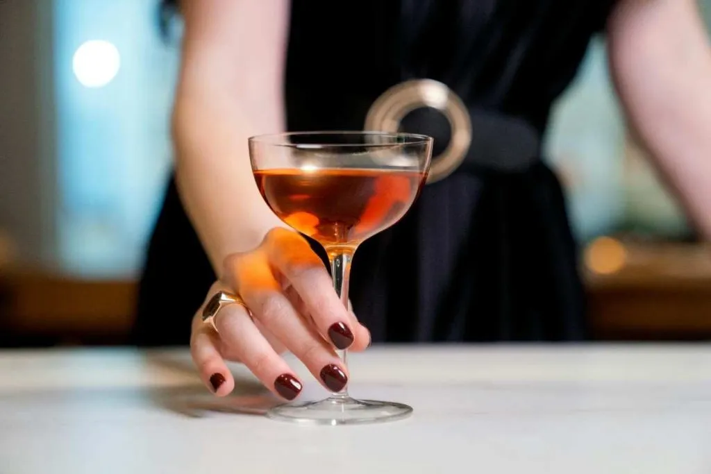 woman's hand on stem of cocktail glass